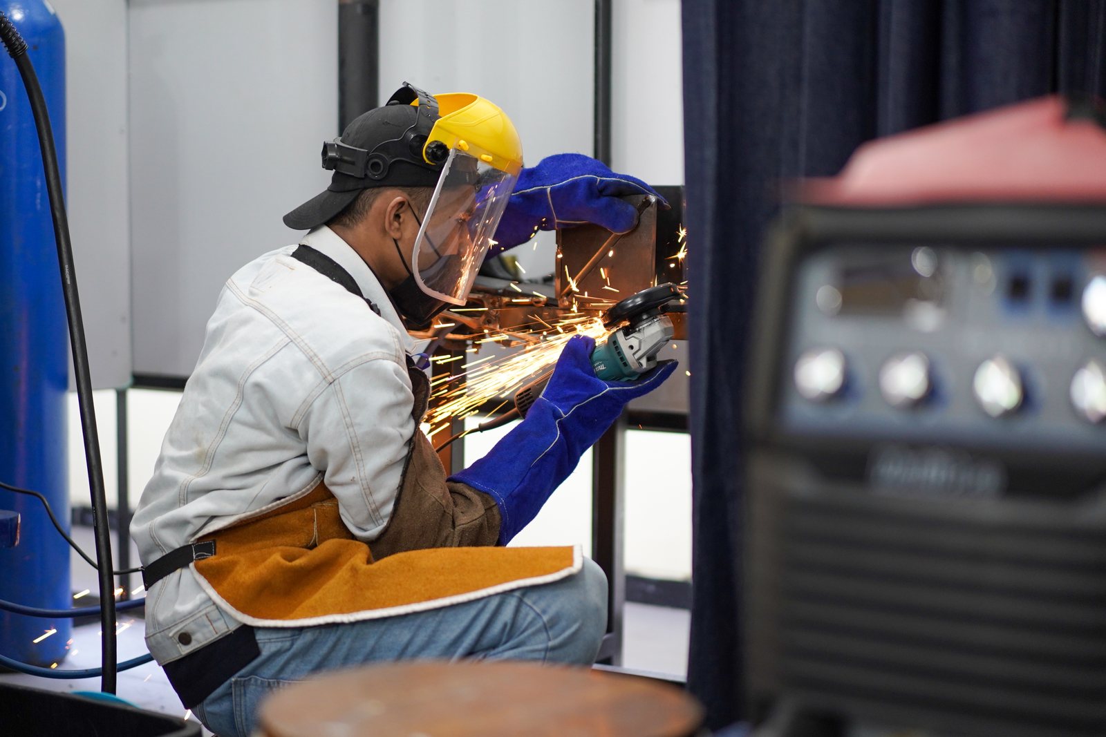 PBD fabricator welding and grinding a custom bracket in the shop